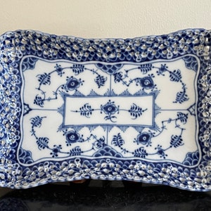 May include: A blue and white porcelain serving tray with a decorative floral pattern and a raised, scalloped edge.
