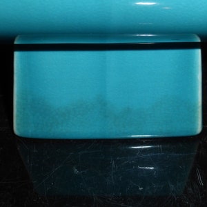Pode incluir: Um vaso de cer&acirc;mica turquesa com base quadrada. O vaso &eacute; feito de cer&acirc;mica esmaltada e tem um acabamento liso.
