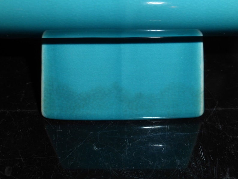Pode incluir: Um vaso de cer&acirc;mica turquesa com base quadrada. O vaso &eacute; feito de cer&acirc;mica esmaltada e tem um acabamento liso.