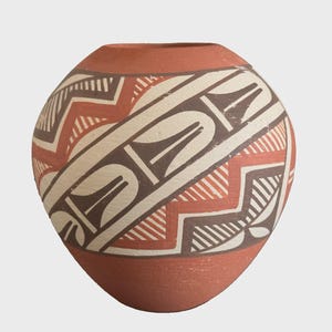 May include: A rounded terracotta vase featuring a wide, central band decorated with dark brown and cream-colored geometric patterns, including zigzags and stylized shapes, set against a matte, reddish-brown clay surface with an open top.
