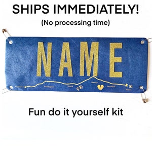 May include: A blue and gold DIY craft kit with the word "NAME" in large gold letters. The kit includes a map of a town with different locations marked with icons. The text "Fun do it yourself kit" is printed below the map.