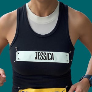 May include: A black tank top with a white name tag pinned to the front. The name tag reads "JESSICA".