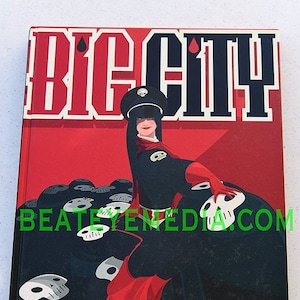 May include: A red and black graphic novel cover with the title "BIG CITY" in bold white letters. A woman in a black military-style uniform and red cape stands in front of a pile of skulls.