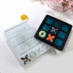 May include: A clear silicone mold with nine different shapes, including squares, circles, and hearts. The mold is filled with colorful resin pieces, including a donut, an X, and a heart. The mold is labeled "See you next time!" and "Irregular shaped layout".
