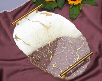 May include: A white and purple resin serving tray with gold flecks and gold metal handles. The tray has an irregular, organic shape.