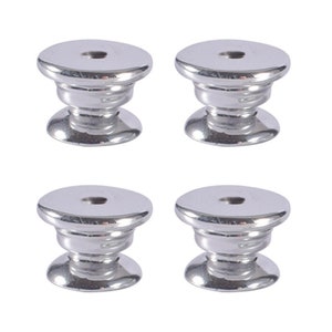 Op de afbeelding: Vier zilveren metalen knoppen met een ronde bovenkant en een verhoogde lip rond de rand. De knoppen hebben een gladde, glanzende afwerking.