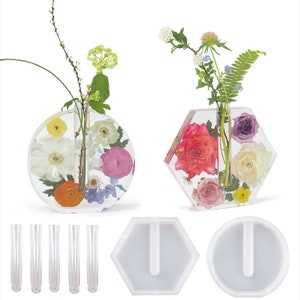 May include: Two clear resin flower vases, one round and one hexagonal, with pressed flowers inside. The vases are shown with five clear glass tubes and two silicone moulds for making similar vases.