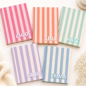 Op de afbeelding: Vijf notitieboeken met harde kaft en verticale strepen in roze, koraal, mintgroen, lavendel en lichtblauw. Elk notitieboek is gepersonaliseerd met een wit naamlabel met de namen CHLOE, ARIA, KATE, SADIE of EMMA in een vetgedrukt lettertype.