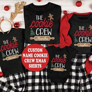 May include: A set of four black t-shirts with a Christmas cookie theme. The shirts feature the text "The Cookie Crew" with a gingerbread man, a Christmas tree, and a rolling pin. Each shirt has a different name on the rolling pin: Bonnie, Martha, Sophia, and Aiden.