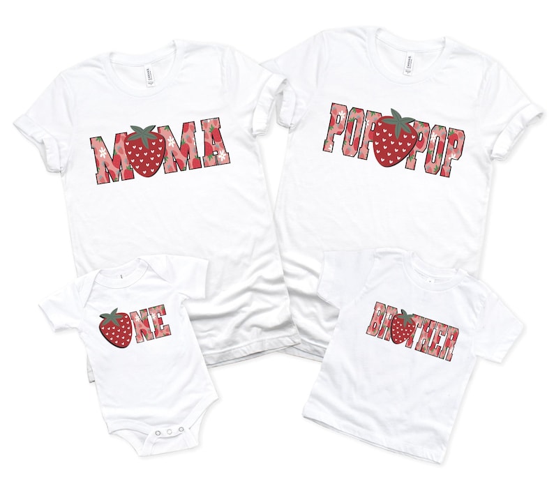 Puede incluir: Dos camisetas blancas de manga corta, un body blanco para beb&eacute; y una camiseta blanca para ni&ntilde;o peque&ntilde;o. Las prendas presentan letras de bloque con estampado de fresas rojas que deletrean MOMA, POP POP, ONE y BROTHER, con una fresa sustituyendo la O.