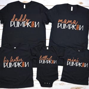 Peut inclure: T-shirts noirs avec un texte sur le thème de la citrouille. Les t-shirts disent "Daddy Pumpkin", "Mama Pumpkin", "Big Brother Pumpkin", "Littlest Pumpkin", et "Mini Pumpkin".
