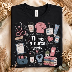 May include: A black t-shirt featuring a graphic print with the text Things a nurse needs surrounded by illustrations of a stethoscope, coffee cup, scrub top, ID badge, hand cream, clipboard, tote bag, pills, gloves, water bottle, and books.
