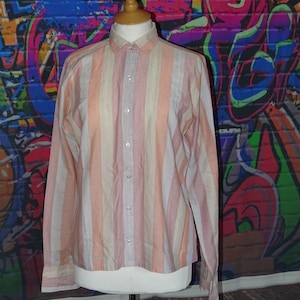 May include: A long-sleeved button-down shirt with vertical stripes in shades of pink, peach, and cream.