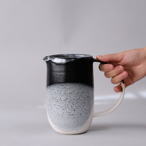 beautiful handmade ceramic water jug or pitcher. Decorated with black and white overlapping glazes which create a modern geometric pattern.