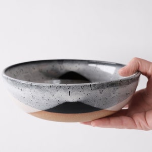 handmade tan stoneware ramen bowl. Two toned black and white overlapping glazes that creates a modern geometric pattern.