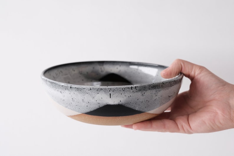 handmade tan stoneware ramen bowl. Two toned black and white overlapping glazes that creates a modern geometric pattern.