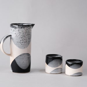 beautiful handmade ceramic water jug or pitcher. Decorated with black and white overlapping glazes which create a modern geometric pattern.
