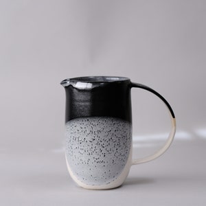 beautiful handmade ceramic water jug or pitcher. Decorated with black and white overlapping glazes which create a modern geometric pattern.