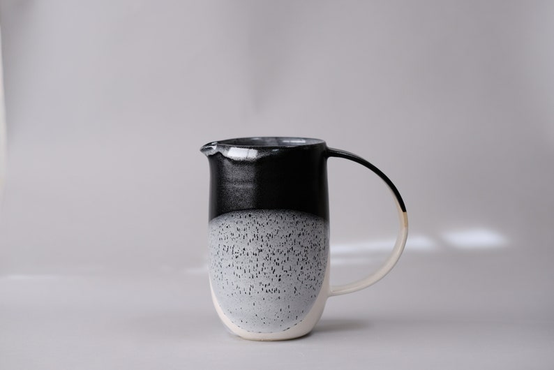 beautiful handmade ceramic water jug or pitcher. Decorated with black and white overlapping glazes which create a modern geometric pattern.