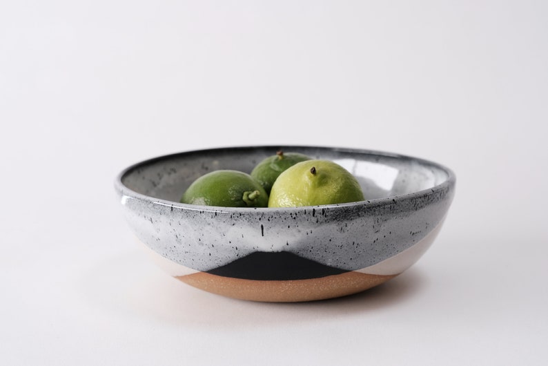 handmade tan stoneware ramen bowl. Two toned black and white overlapping glazes that creates a modern geometric pattern.