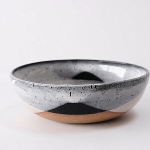 handmade tan stoneware ramen bowl. Two toned black and white overlapping glazes that creates a modern geometric pattern.