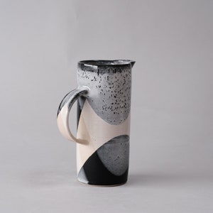 beautiful handmade ceramic water jug or pitcher. Decorated with black and white overlapping glazes which create a modern geometric pattern.