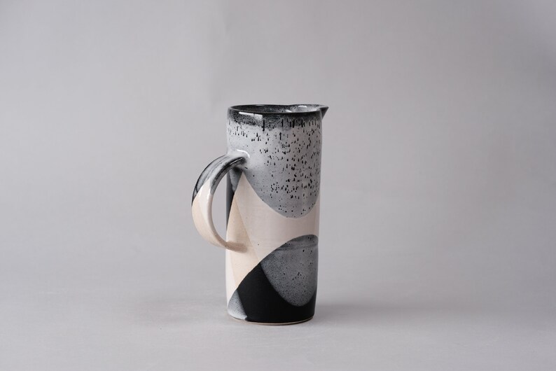 beautiful handmade ceramic water jug or pitcher. Decorated with black and white overlapping glazes which create a modern geometric pattern.