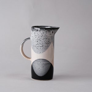 beautiful handmade ceramic water jug or pitcher. Decorated with black and white overlapping glazes which create a modern geometric pattern.