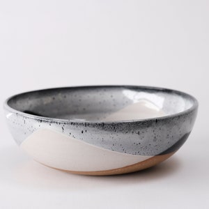 handmade tan stoneware ramen bowl. Two toned black and white overlapping glazes that creates a modern geometric pattern.