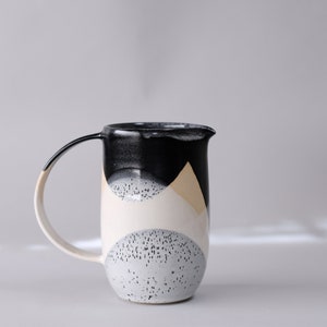 beautiful handmade ceramic water jug or pitcher. Decorated with black and white overlapping glazes which create a modern geometric pattern.