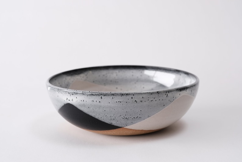 handmade tan stoneware ramen bowl. Two toned black and white overlapping glazes that creates a modern geometric pattern.