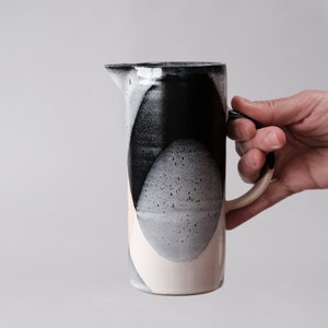 beautiful handmade ceramic water jug or pitcher. Decorated with black and white overlapping glazes which create a modern geometric pattern.