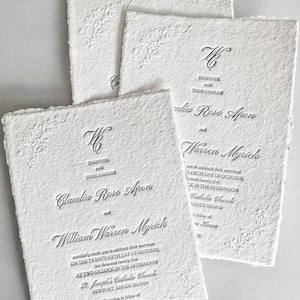 May include: White wedding invitations with embossed floral corner designs and elegant script. The invitations include the names Claudia Rose Apon and William Warren Myrick, along with event details.