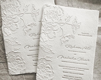 May include: Two off-white wedding invitation cards featuring a raised, embossed floral design. The text reads: Together with their families, Raheem Ali and Maleiha Nazir request the pleasure of your company to celebrate their wedding, Sunday 10th August 2025, guest arrival from 2pm, Hardwick Hall, Sedgefield, TS21 2EH.