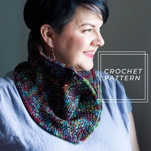 May include: A woman wearing a colorful crocheted cowl neck scarf. The scarf is made with a variety of colors, including purple, blue, green, and red. The text "CROCHET PATTERN" is visible in a white box.