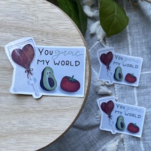 May include: Three stickers with a heart-shaped balloon, avocado, and tomato. The text on the stickers reads "You guac my world".