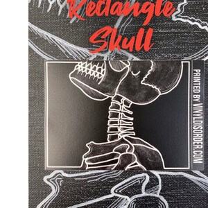 May include: Black and white sticker featuring a skull and spine illustration. The sticker is rectangular and has the text "PRINTED BY VINYLDISORDER.COM" on the right side.