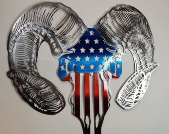 May include: Metal wall art sculpture of a ram skull with an American flag design. The skull is silver and the flag is red, white, and blue.