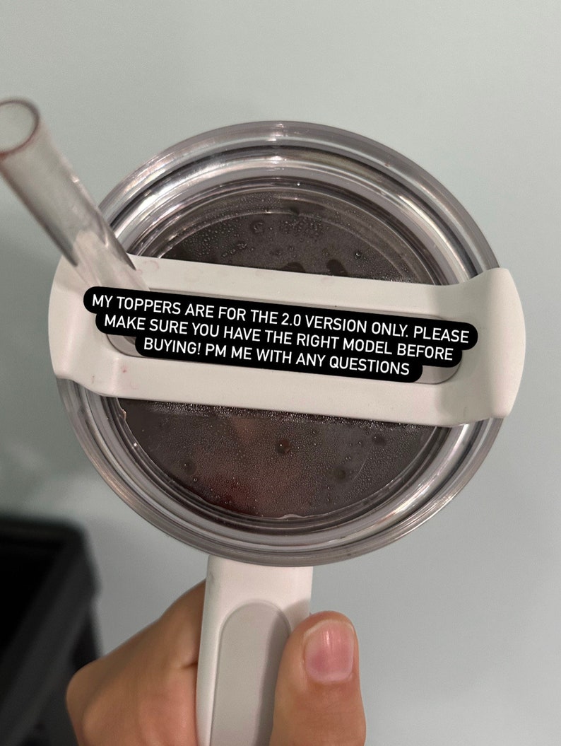 May include: A clear, round tumbler lid with a white handle and straw. The lid has a white plastic holder for the straw. Text on the lid reads: "MY TOPPERS ARE FOR THE 2.0 VERSION ONLY. PLEASE MAKE SURE YOU HAVE THE RIGHT MODEL BEFORE BUYING! PM ME WITH ANY QUESTIONS."