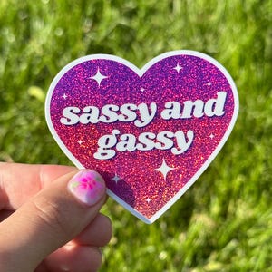 May include: Pink heart-shaped sticker with glitter and the text "sassy and gassy" in white.