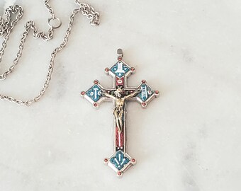 May include: A silver chain necklace with a silver and enamel cross pendant. The cross is decorated with blue, red, and white enamel and features a small figure of Jesus Christ.