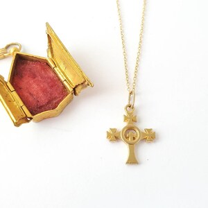 May include: A gold-tone necklace with a cross pendant. The cross has a circle in the center with a smaller cross inside. The necklace is on a white background.