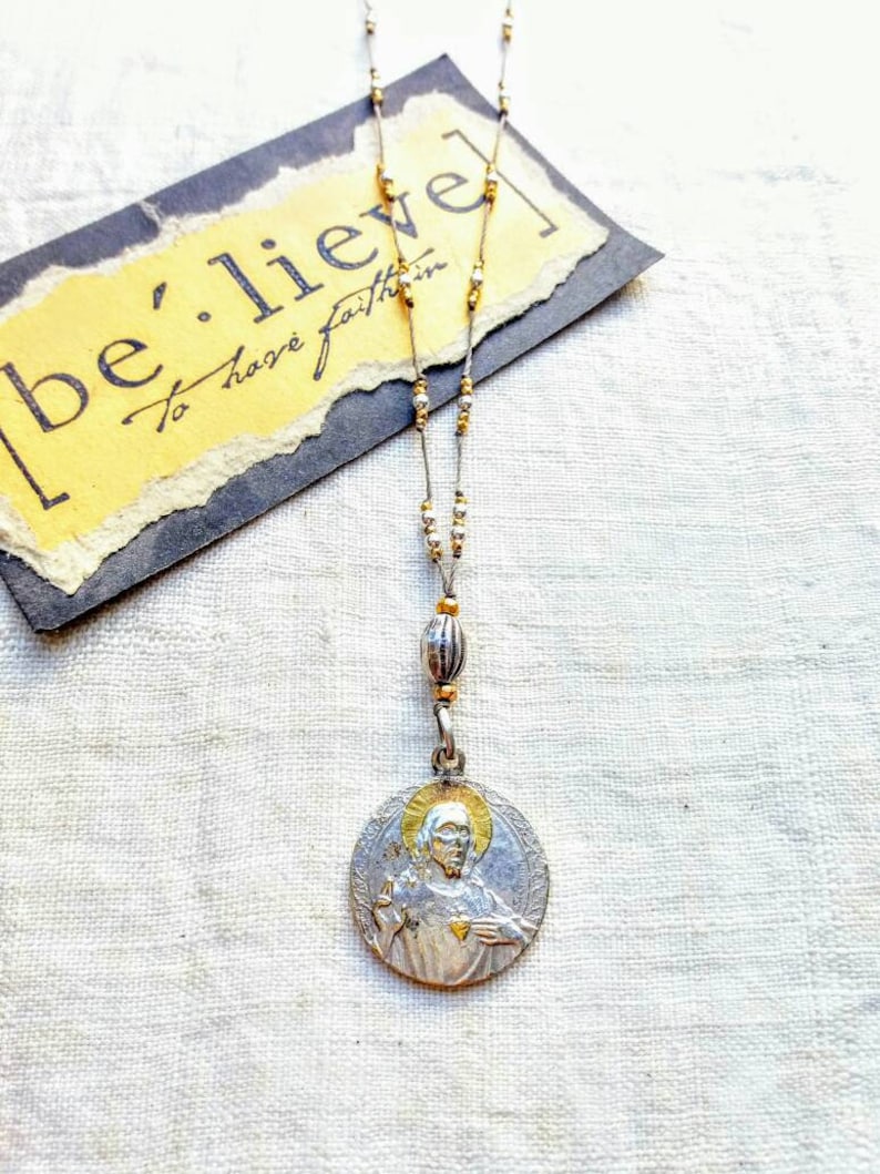 Antique silver and gold sacred heart necklace .