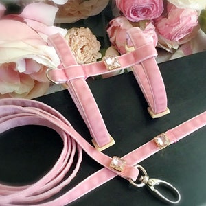 May include: Pink velvet dog harness and leash set with crystal embellishments. The harness has a  adjustable chest strap and the leash has a metal clip.