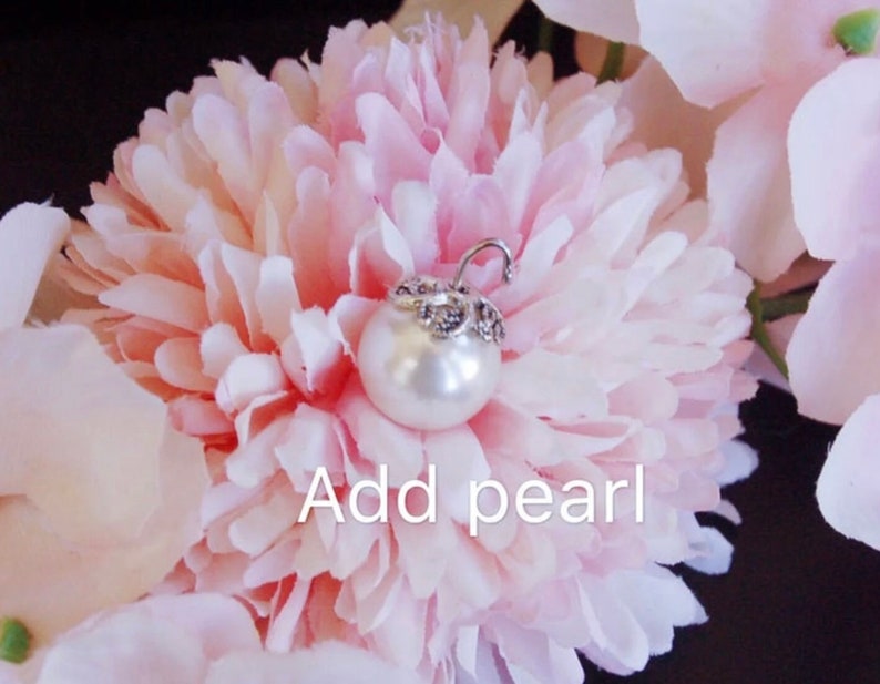 May include: A white pearl with a silver setting is placed on a pink flower. The text "Add pearl" is written below the pearl.