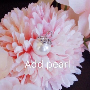 May include: A white pearl with a silver setting is attached to a pink flower. The text "Add pearl" is written below the pearl.