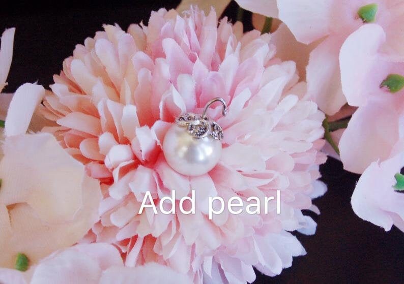 May include: A white pearl with a silver setting is attached to a pink flower. The text "Add pearl" is written below the pearl.