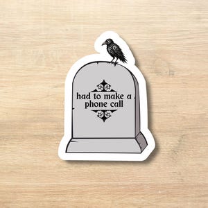 Puede incluir: Una pegatina con una lápida gris con la frase "had to make a phone call" en texto negro. Un cuervo negro está posado encima de la lápida. La pegatina tiene un borde blanco.