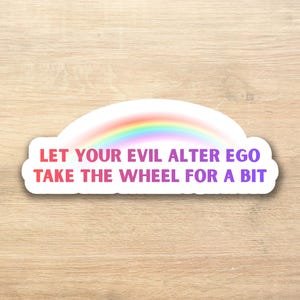 Könnte beinhalten: Ein weißer Aufkleber in Wolkenform mit einem Regenbogen und dem Text "LET YOUR EVIL ALTER EGO TAKE THE WHEEL FOR A BIT" in Rosa und Lila.