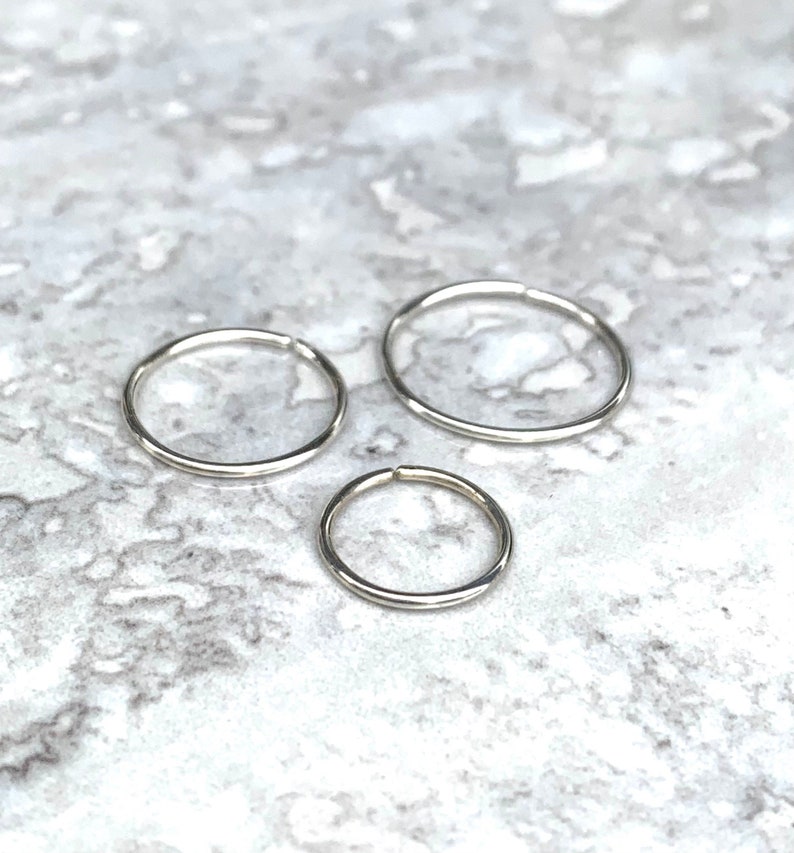 Three Class X minimalist plain sterling silver no clasp hoops in sizes 6mm, 8mm and 10mm on white and black marble tile